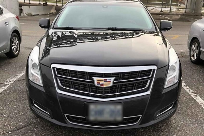 A black Cadillac with a visible emblem and a blurred license plate. 1