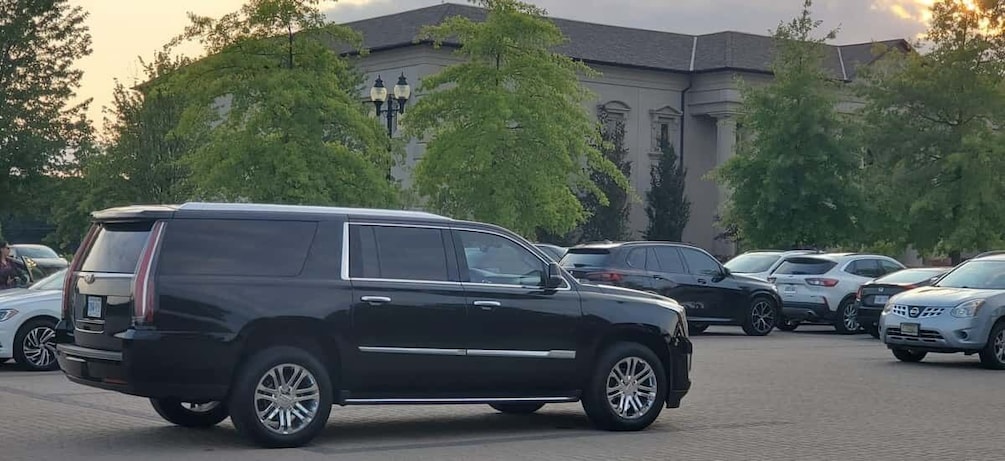 A black SUV parked in a lot with trees and a building in the background. 2