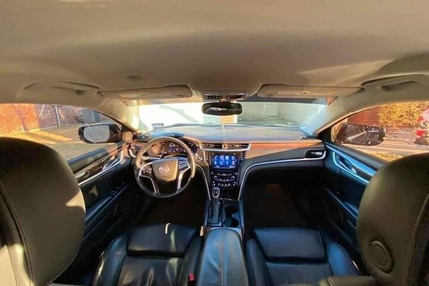 The interior of a car with a steering wheel, dashboard, and leather seats. 5