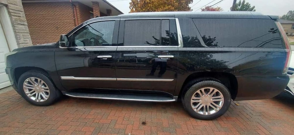 A black SUV parked on a brick driveway. 3