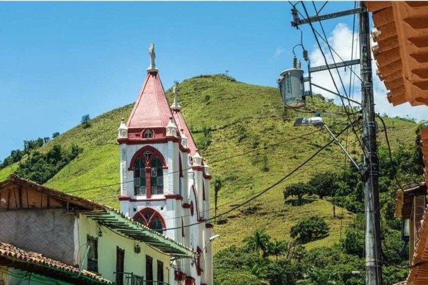 A church with a red roof and white walls, a hill in the background, and power lines. 5
