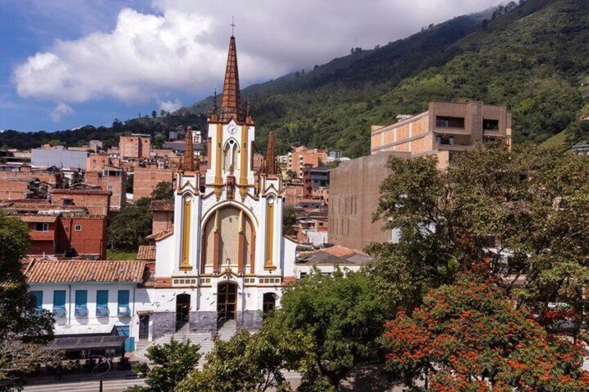 A church with a tall spire, surrounded by urban buildings and greenery. 2