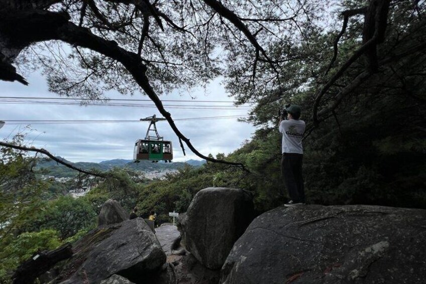 A person standing on a rock, overlooking a cable car in a mountainous area. 5