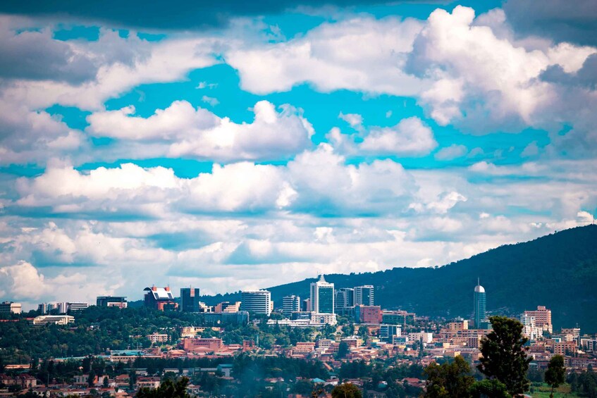 A cityscape with a mountain backdrop, featuring a prominent skyscraper and dense urban buildings. 3