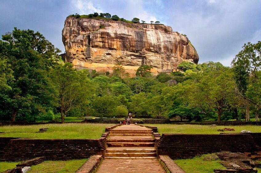 A large rock formation with a staircase leading up to it, surrounded by trees. 1