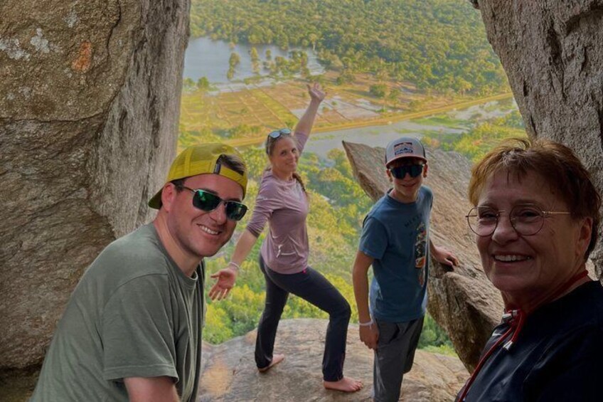 Three people standing on a rocky outcrop with a view of a valley below. 5