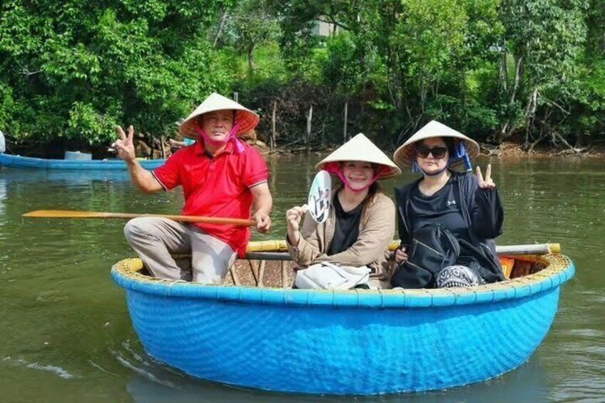 Three people in a blue boat on a river, wearing conical hats. 5