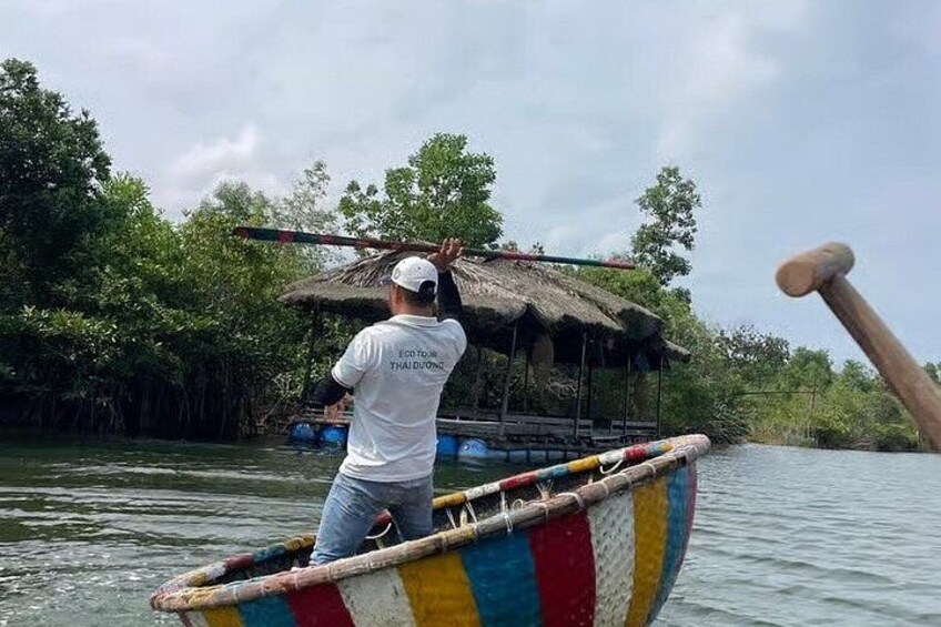 A person paddling a colorful boat with a thatched roof structure on it. 1