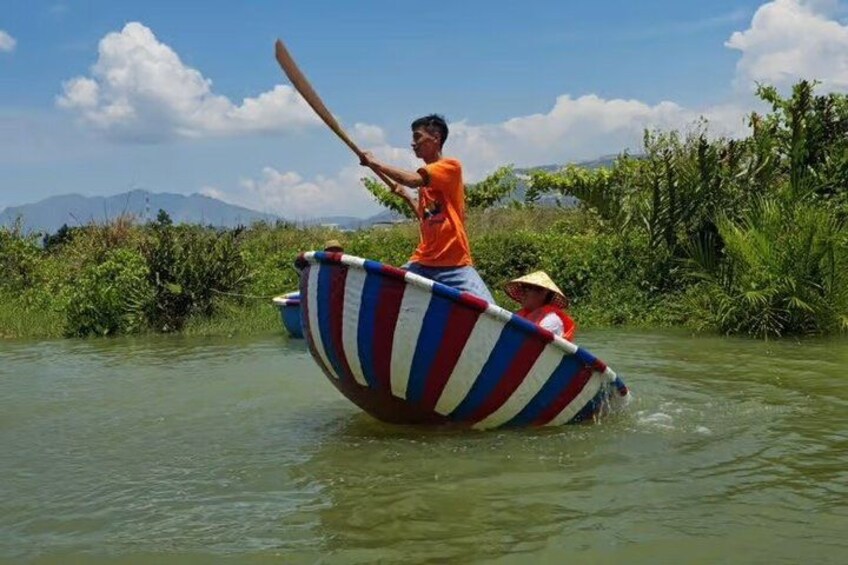 A person paddling a boat with a striped design, surrounded by greenery and water. 4