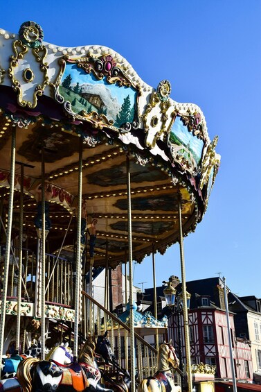 A carousel with ornate decorations and horses, set against a clear blue sky. 5