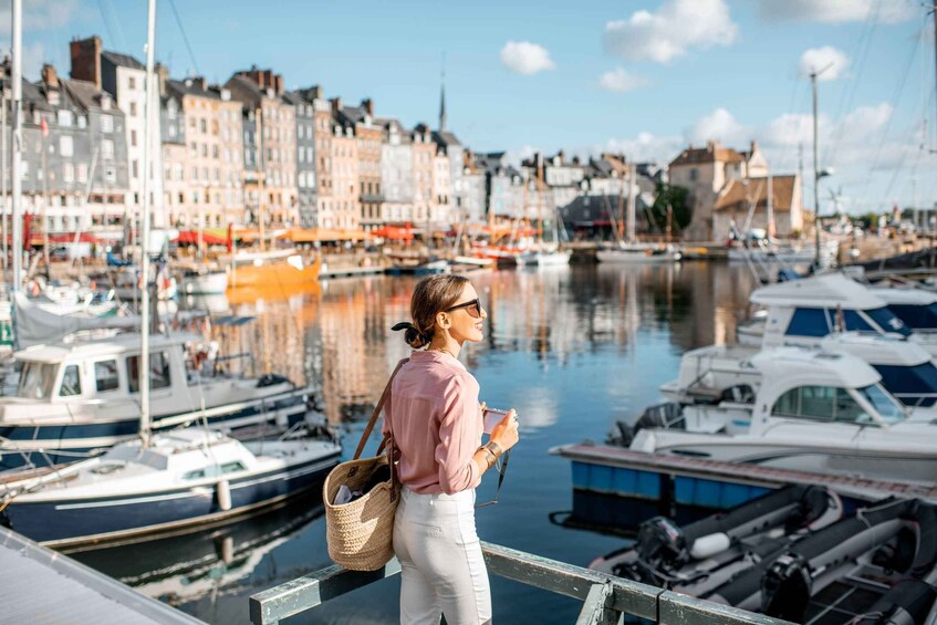 A person standing by a marina with boats and buildings in the background. 1