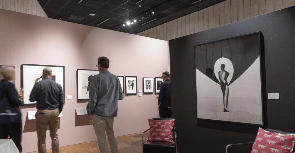 An art gallery with people viewing artworks on the wall. 3