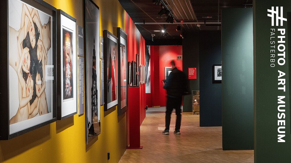 An art museum interior with red walls and yellow accents, featuring framed artworks on display. 5