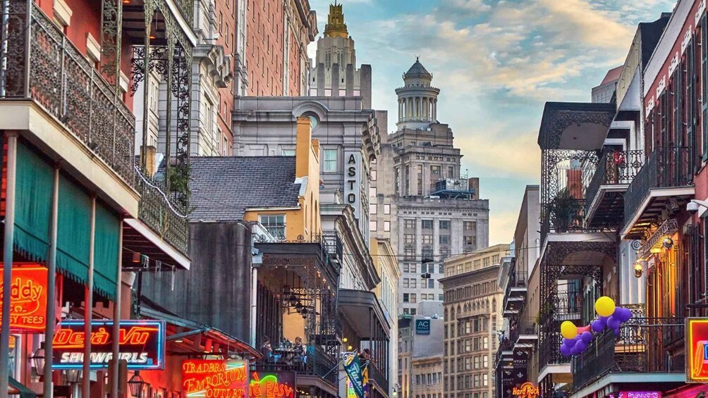 A bustling urban street lined with historic buildings, neon signs, and a clear sky. 2
