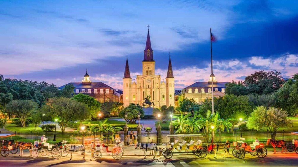 A historic cathedral with three spires, surrounded by lush greenery and horse-drawn carriages. 3