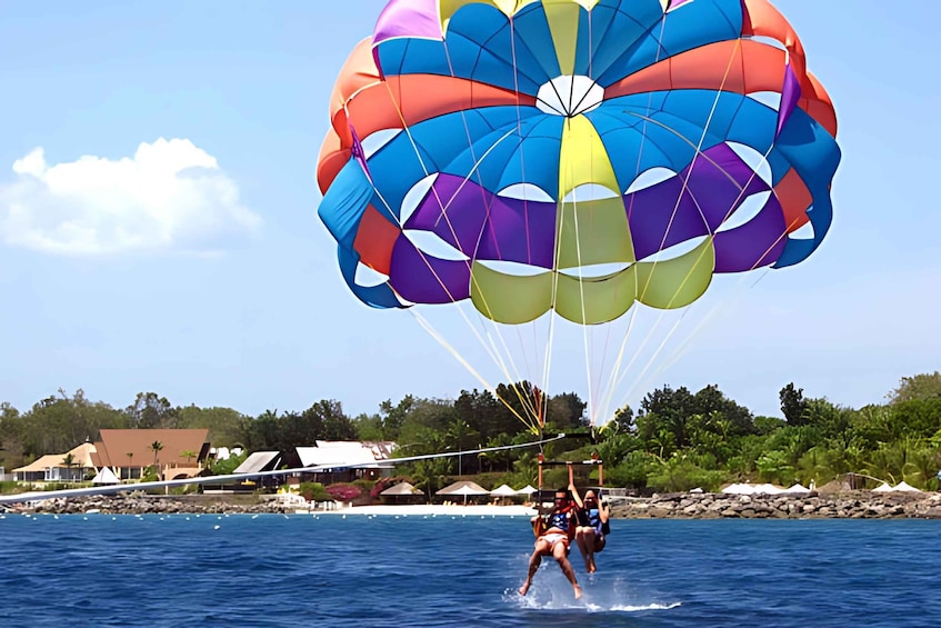 Two people parasailing over water with a colorful parachute. 5