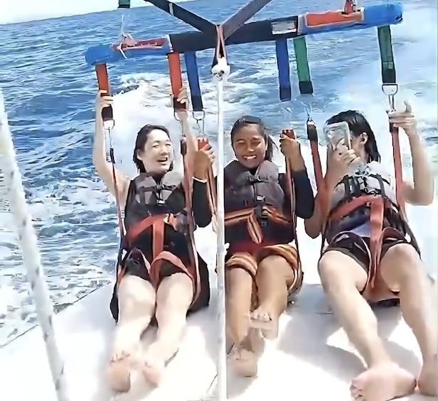 Three people on a boat with a canopy, wearing life jackets, and holding onto the canopy's ropes. 2