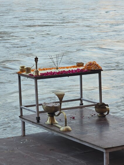 A metal table with ritual items by a body of water. 2