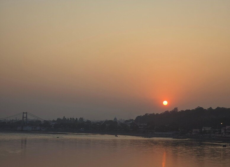 A sunset over a river with a bridge and buildings in the background. 1