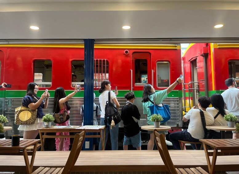 A group of people taking photos in front of a red train. 3
