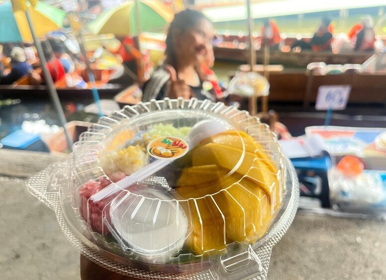 A food stall with a plastic container holding mango slices and other food items. 2