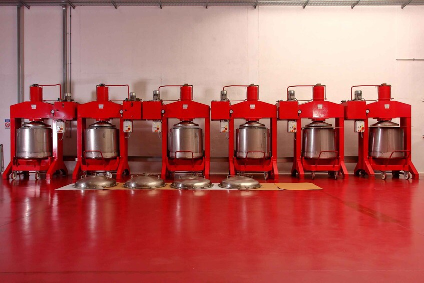 Six red industrial machines with metallic tanks, arranged in a row on a red floor. 5