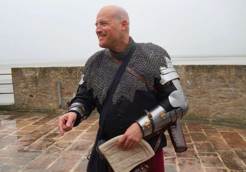 A person in medieval armor with a chainmail shirt, holding a shield, standing on a stone pavement. 4