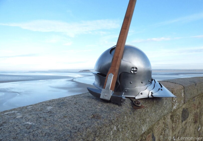 A medieval helmet with a wooden handle on a stone surface. 5