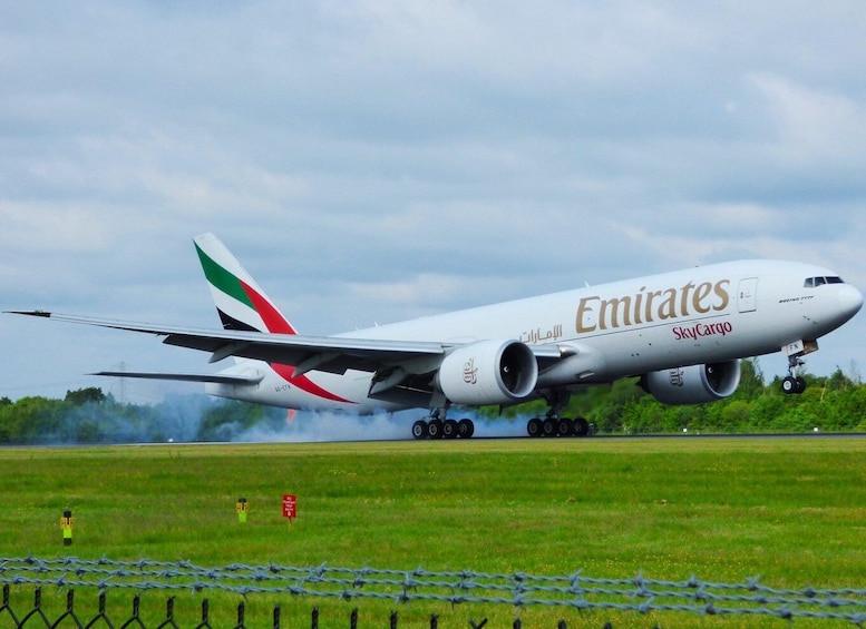 An Emirates SkyCargo airplane on the runway with smoke from its engines. 3
