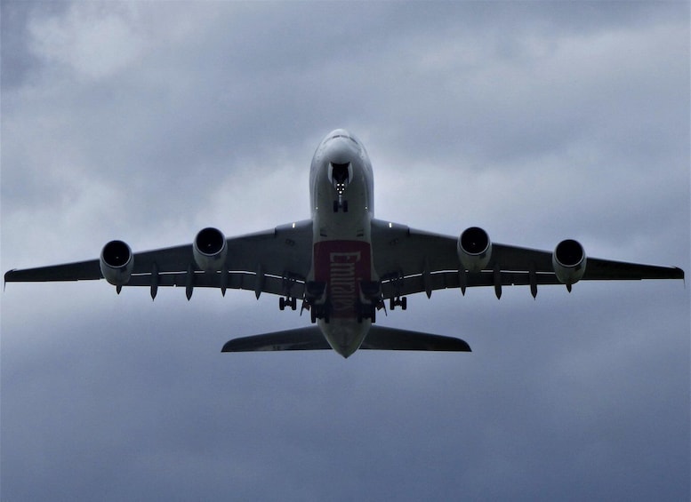 A large commercial airplane in flight with four engines, a red and white fuselage, and a cloudy sky in the background. 5