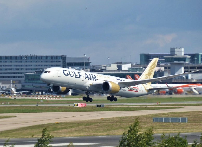 A Gulf Air airplane on the runway with airport buildings in the background. 4