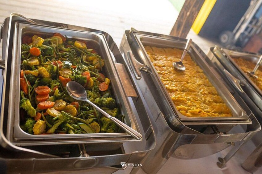 A buffet with various dishes, including a tray of mixed vegetables and a tray of what appears to be a curry or stew. 5