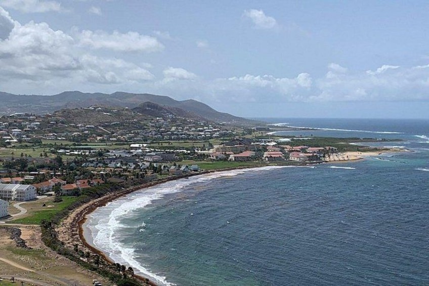 A coastal town with a beach, ocean waves, and distant mountains. 4