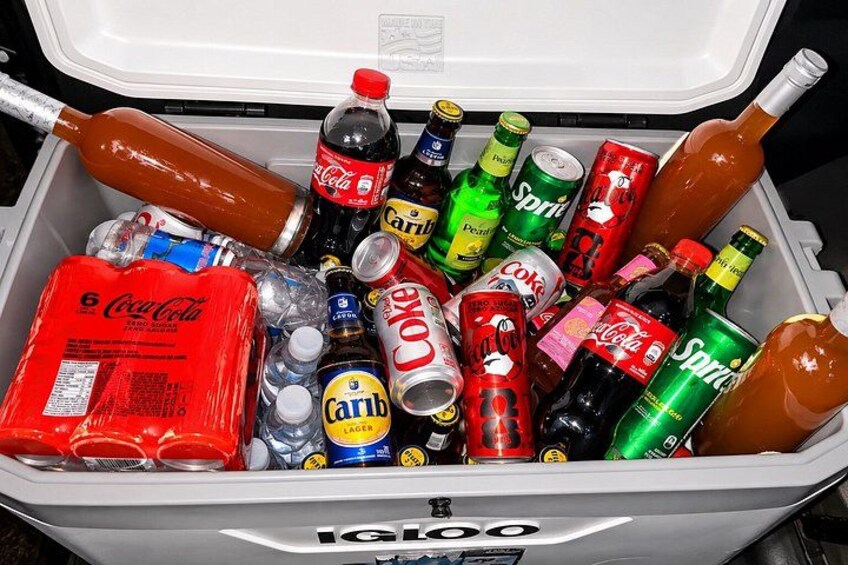 A cooler filled with various beverages including soda cans, bottles, and a large bottle of syrup. 4