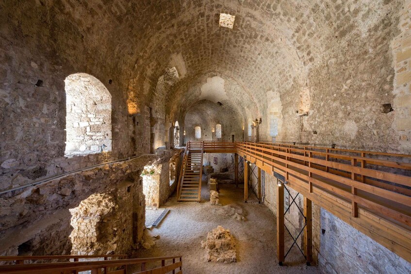 An ancient stone structure with arched passageways, wooden railings, and a central staircase. 4