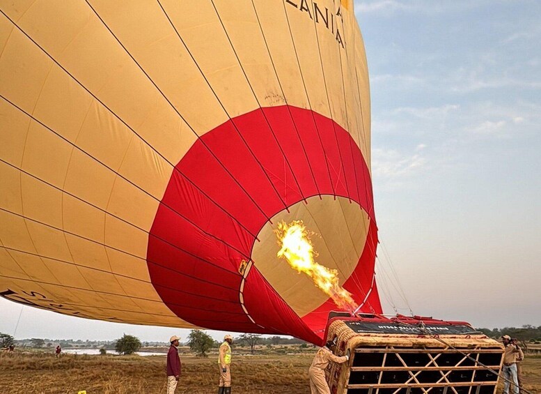 A hot air balloon with flames at the basket, being prepared for launch. 1