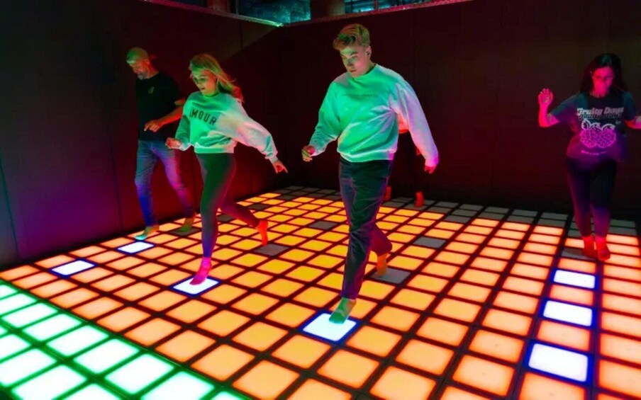People dancing on a floor with illuminated tiles. 1