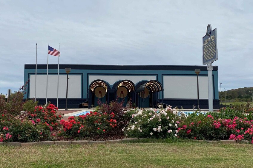 A building with a signboard, American flag, and a garden with flowers. 1