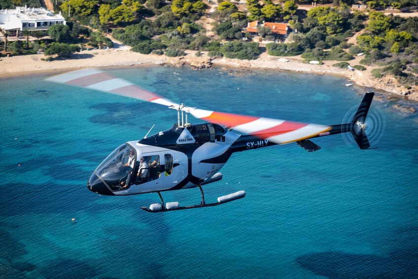A helicopter flying over a coastal area with clear blue water and a beach in the background. 4