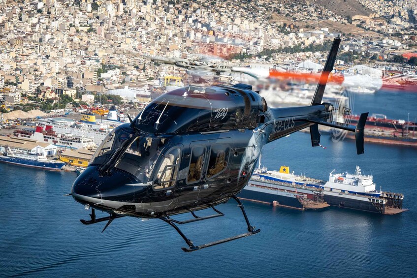 A helicopter flying over a coastal city with a large ship docked nearby. 3