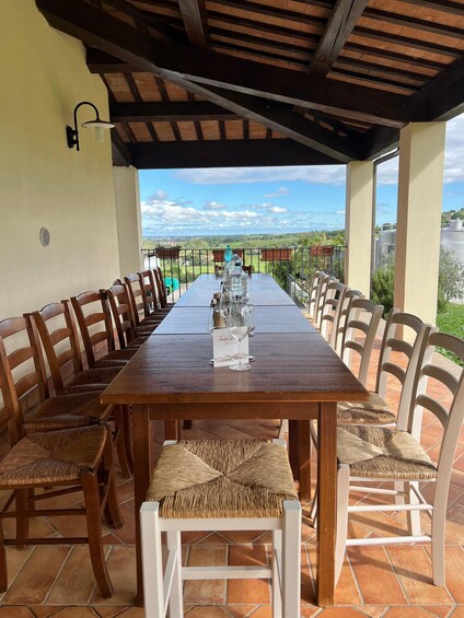 An outdoor dining area with a long wooden table, wicker chairs, and a view of the countryside. 5