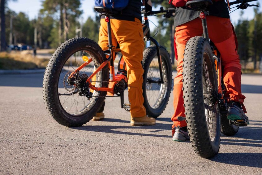 Two people standing next to bicycles on a paved surface. 3