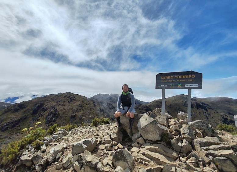 A hiker at Cerro Chirripó with a sign indicating the altitude of 3,820 meters and 12,533 feet. 1