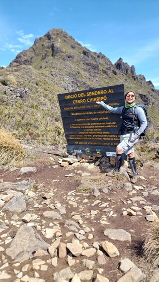 A hiker at the start of a trail with a sign indicating the beginning of Sendero al Cerro Chiripó, a high-altitude trek. 4