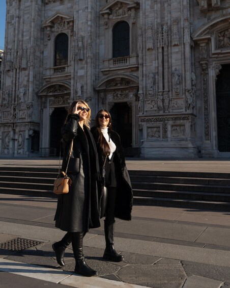 Two people walking in front of a historic building with intricate architecture. 4