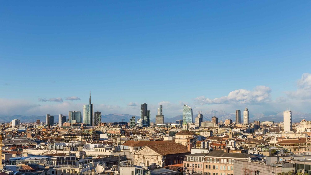 A cityscape with a mix of modern skyscrapers and historic buildings, a clear sky, and distant mountains. 2
