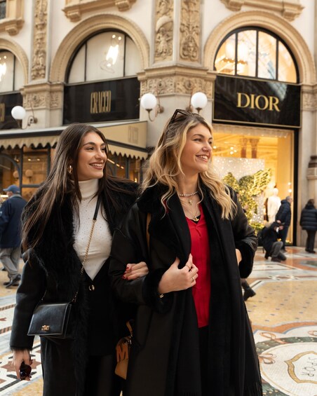 Two women walking in a shopping area with stores like DIOR and CANNY visible. 5