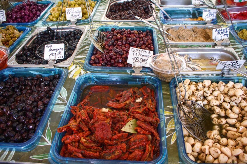 A variety of olives and pickled vegetables in glass containers at a market. 3