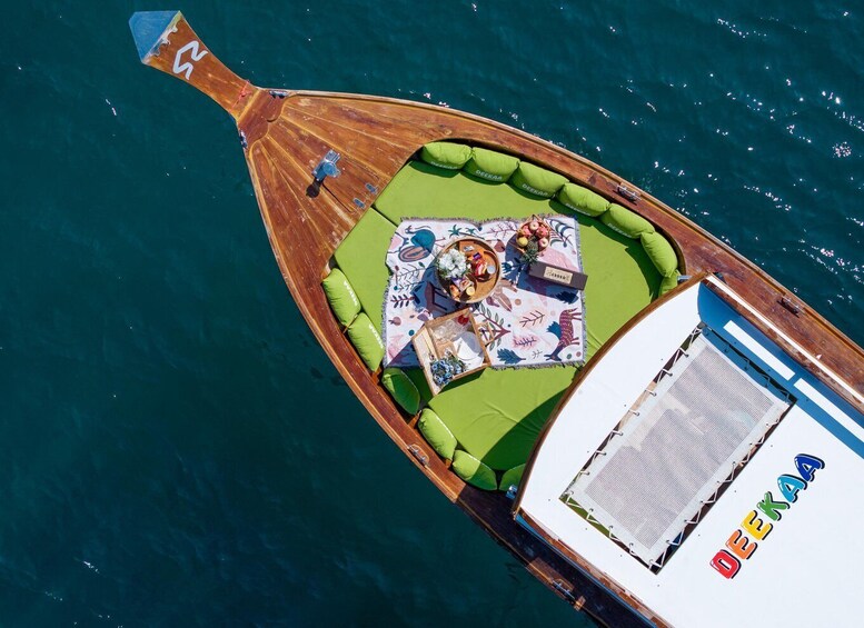 A boat with a green deck area, a table set with food and drinks, and the name 'DEKAA' on the side. 2