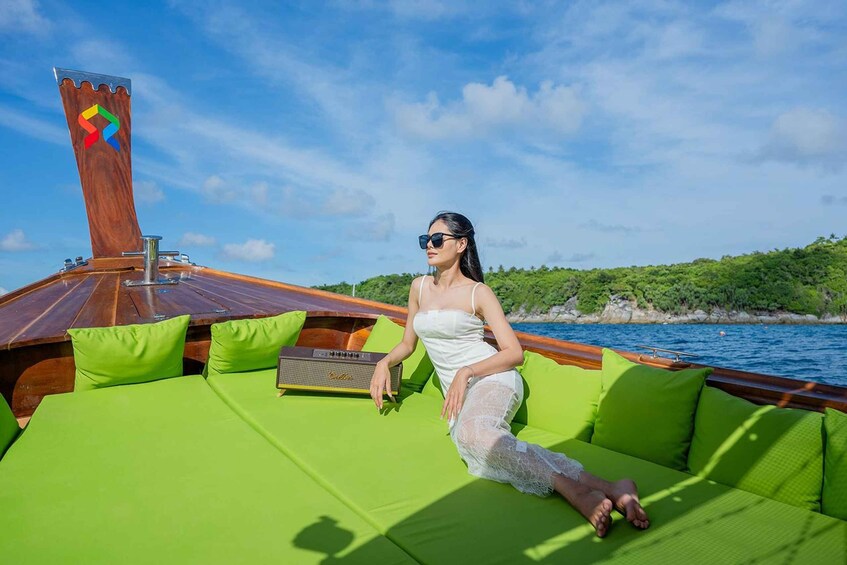 A woman sitting on a green cushioned deck of a boat with a wooden structure and a colorful logo. 4